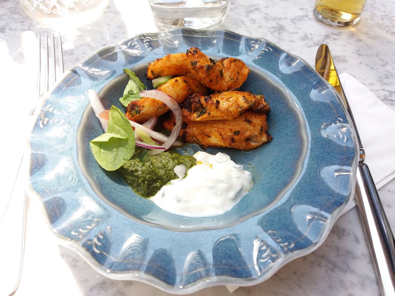 Grilled chicken tikka plated with raw onion, lime and a green chutney