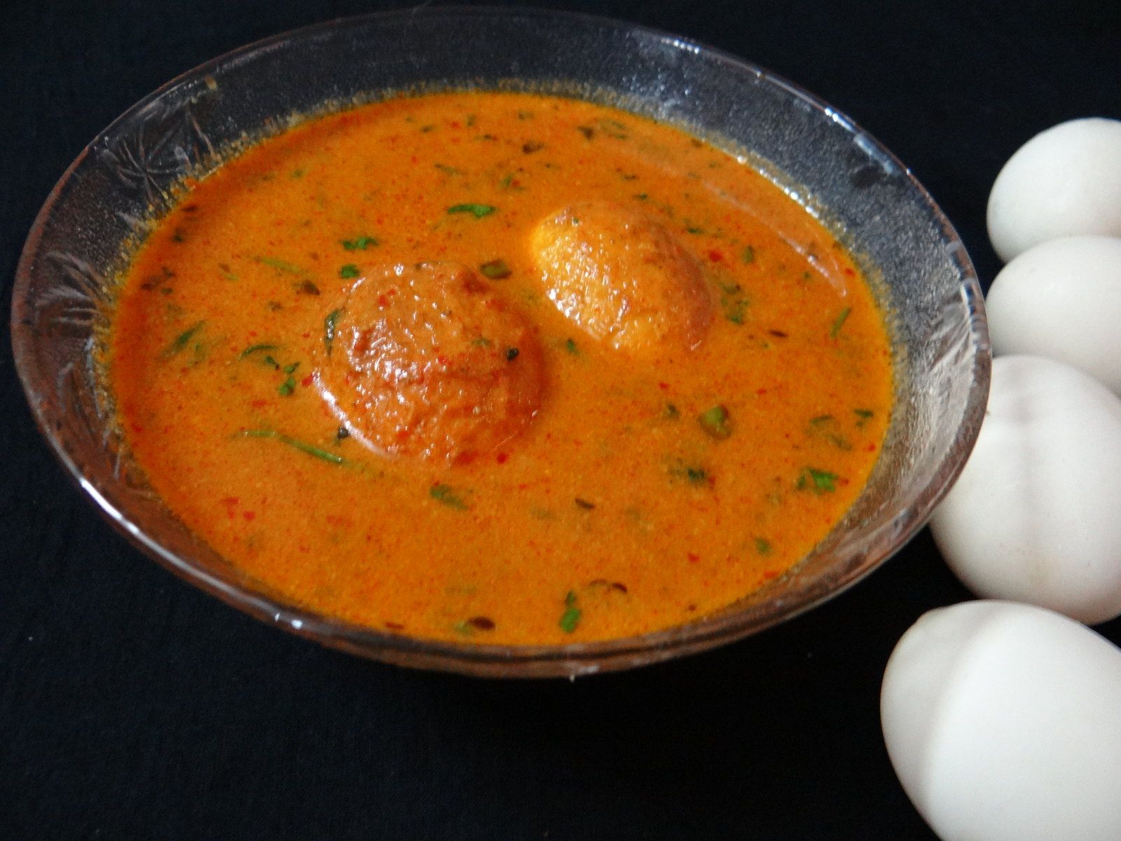 Halved soft-boiled eggs resting in a thick tomato and herb sauce