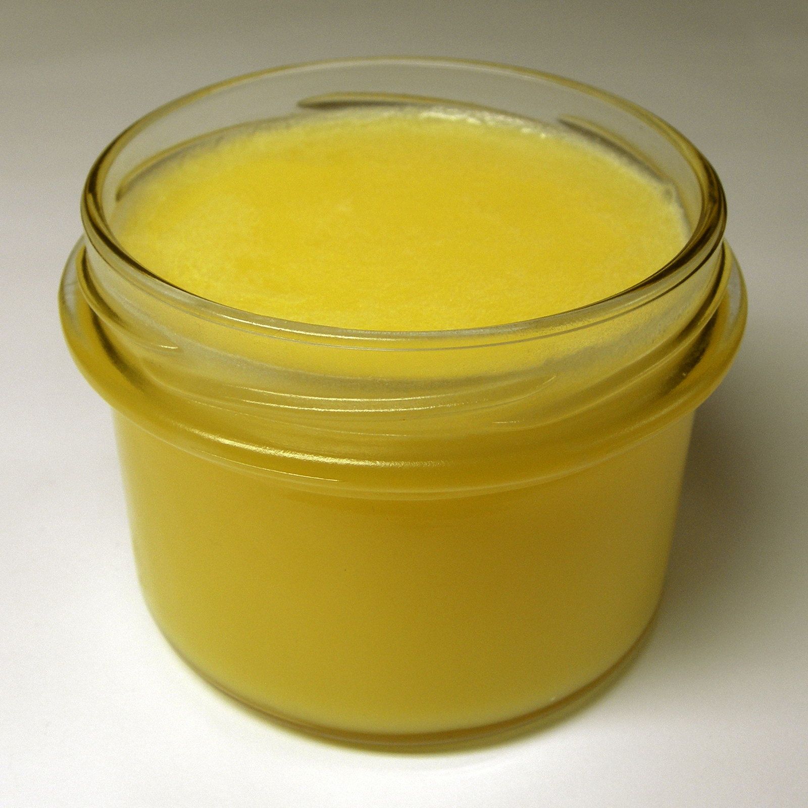 An open jar of clarified butter, set against a clean white backdrop