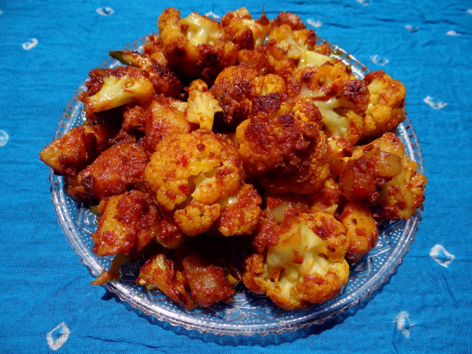 Spiced cauliflower florets in a steel bowl against a dark backdrop