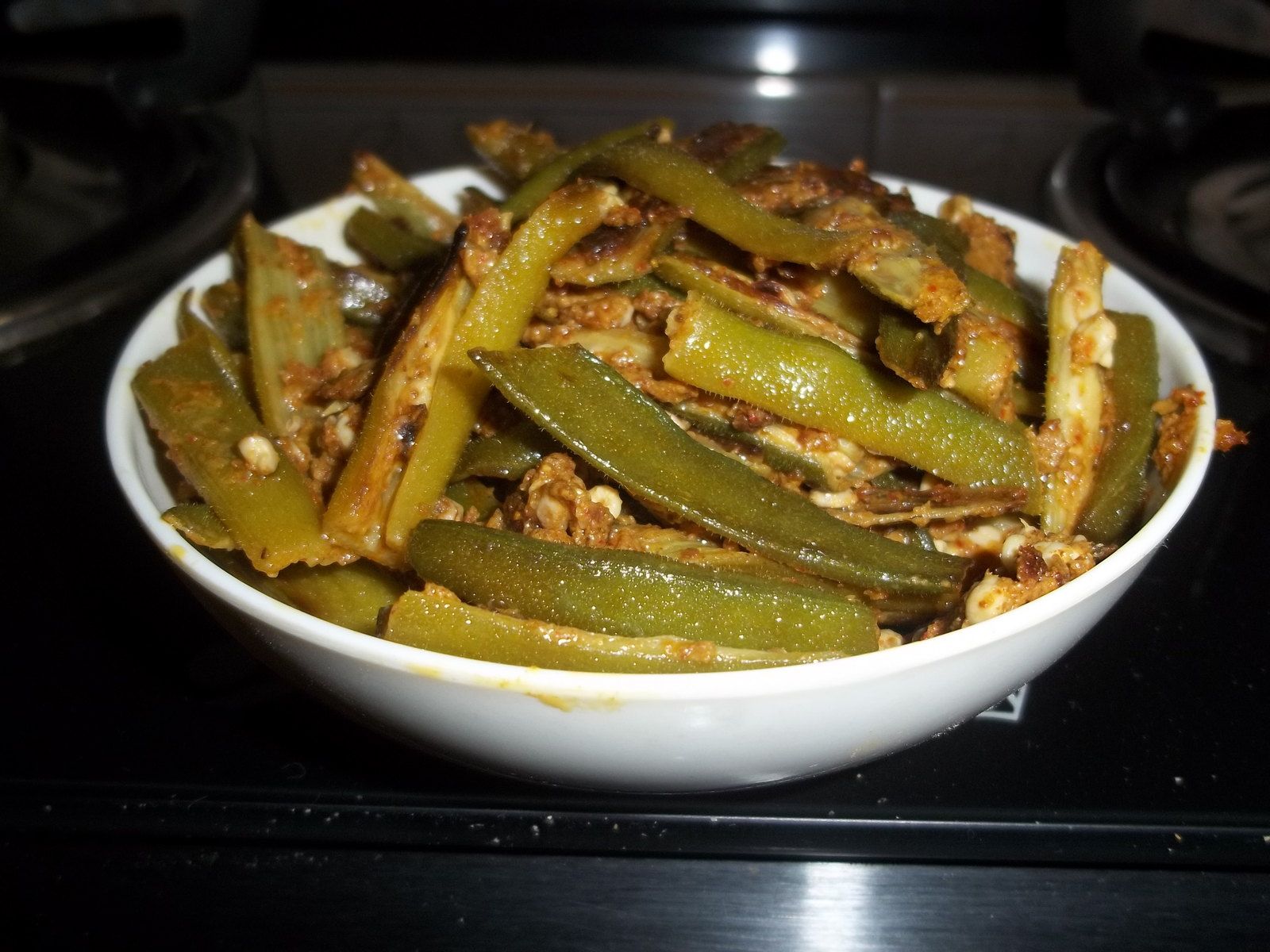 Sliced okra fried with onion and spice, served in a plain white bowl
